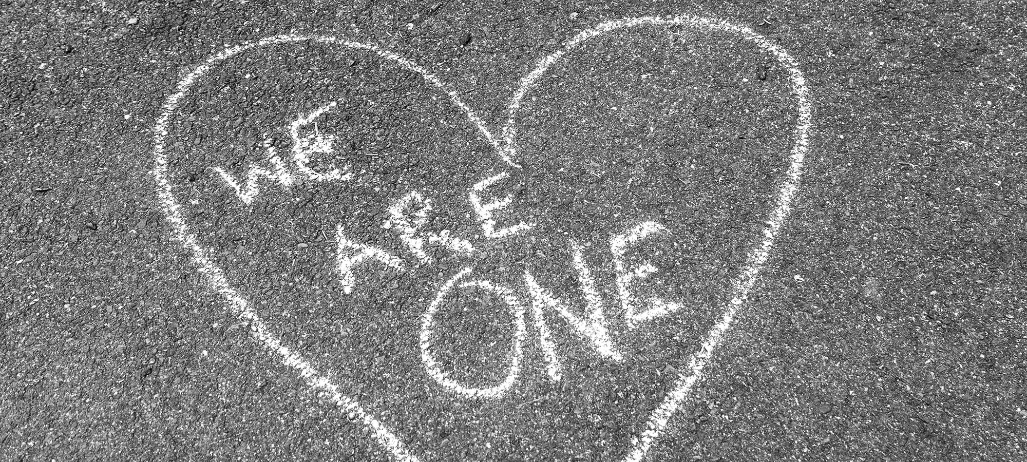 Heart drawn in chalk on the ground with the words 'we are one'