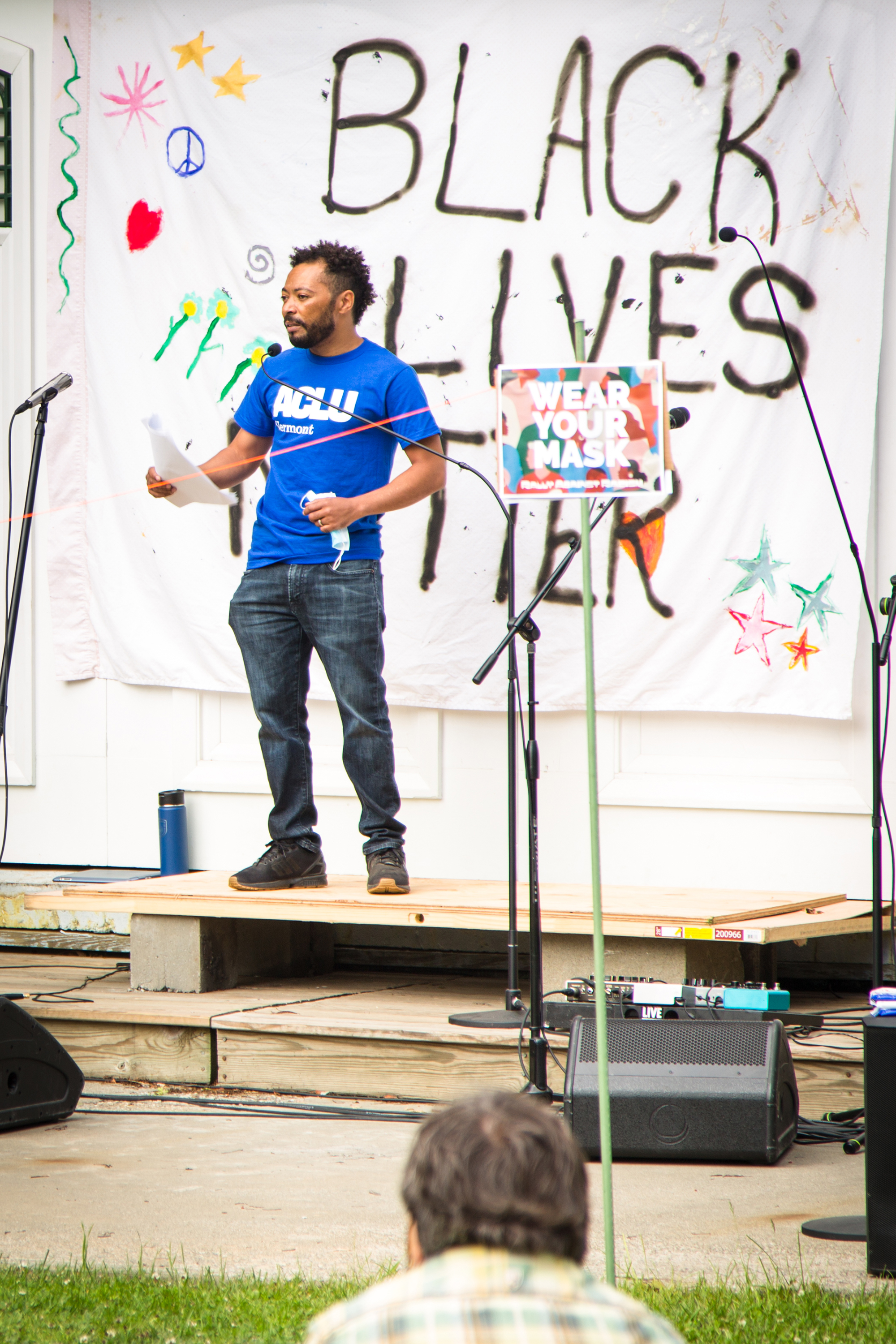 Speaker on a stage in front of a 'BLACK LIVES MATTER' banner