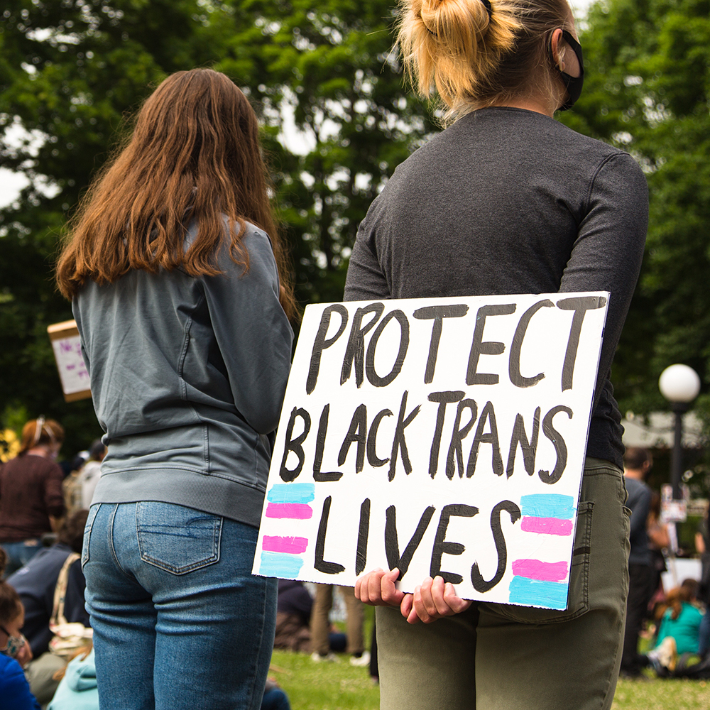 Person holding a sign that reads'PROTECT BLACK TRANS LIVES'